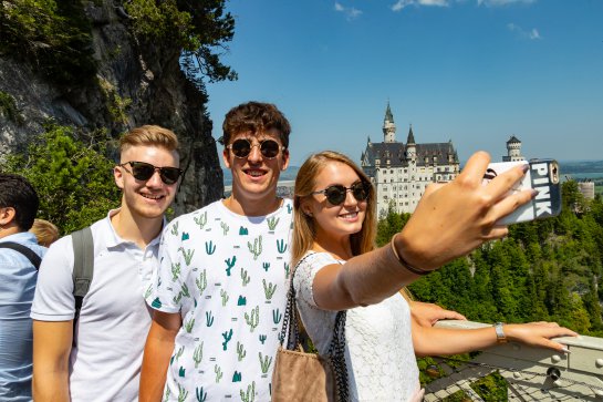 Freundesgruppe macht Selfie vor Schloss Neuschwanstein